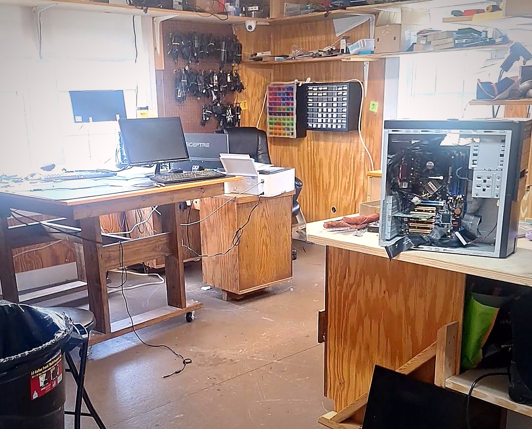 Inside the Schmidt Sales & Service repair shop in Macon, Mississippi: workbenches with an open desktop tower, diagnostics monitor, cable racks and parts bins