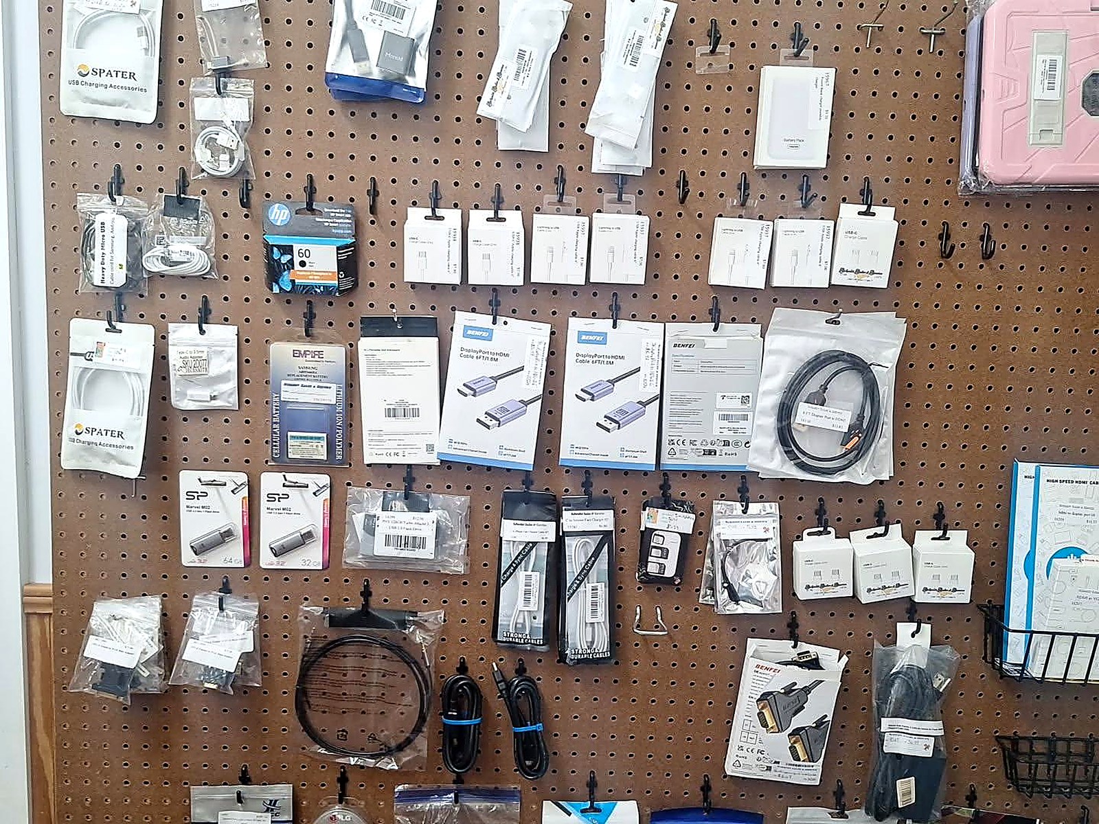 Pegboard wall of USB charging cables, HDMI and DisplayPort adapters, flash drives and replacement batteries for sale